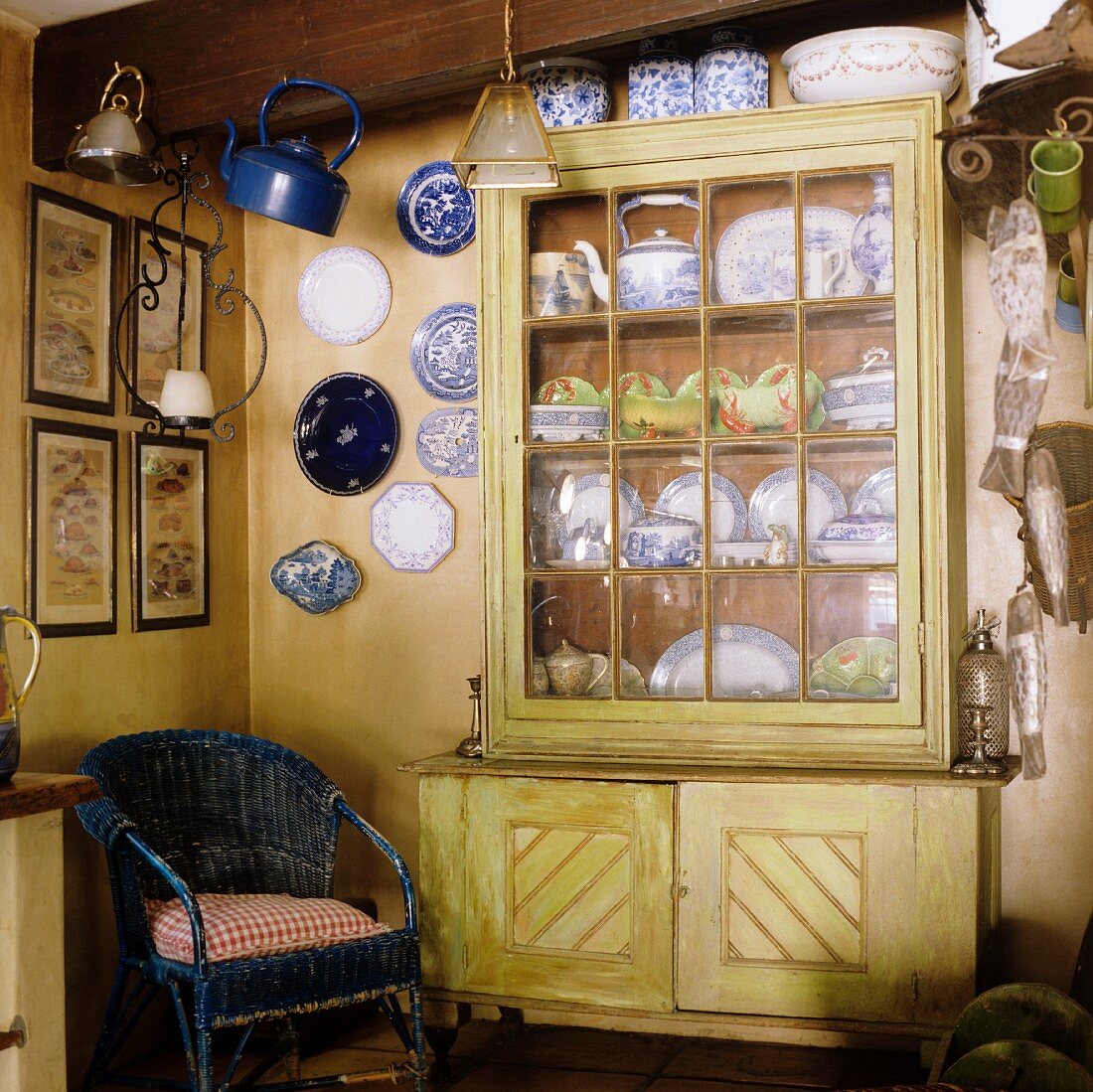 Blauer Korbsessel und Wandteller in der Ecke neben Geschirrschrank