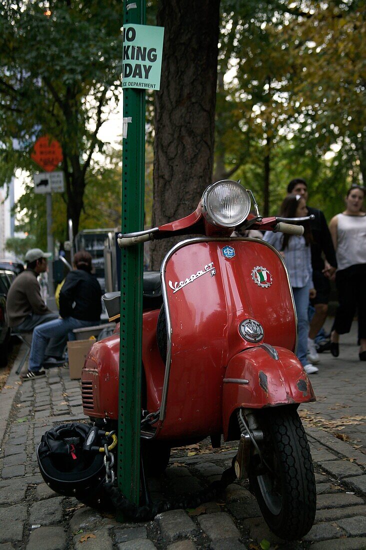 Vespa Gran Turissimo motor scooter chained to post near Central Park, Manhattan, New York, NY.