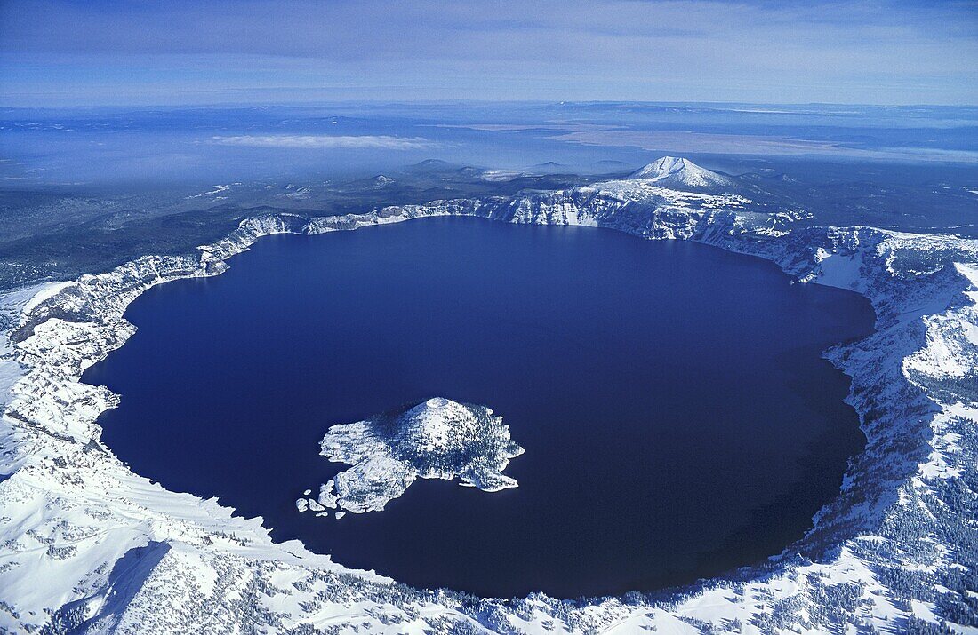 "Wizard Island and Crater Lake in winter snow; Crater Lake National Park, Oregon."
