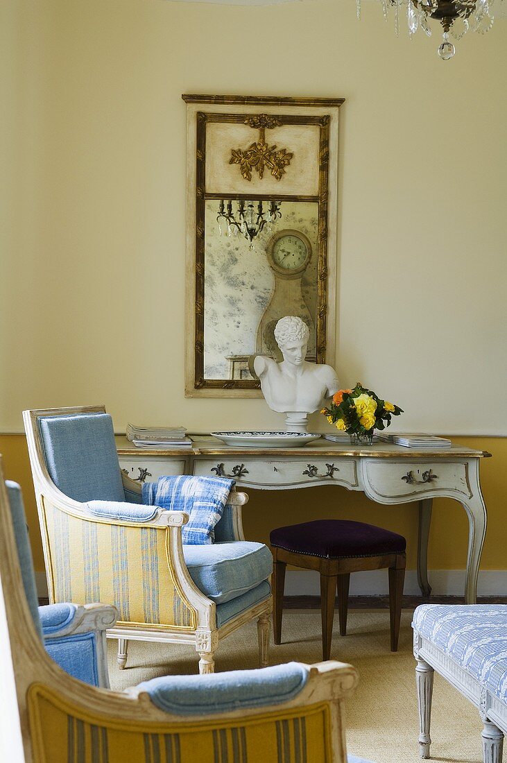 An antique armchair with a striped cover and a delicate, Rococo-style wall table