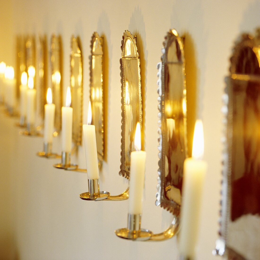 A romantic atmosphere - burning candles in brass-coloured wall holders