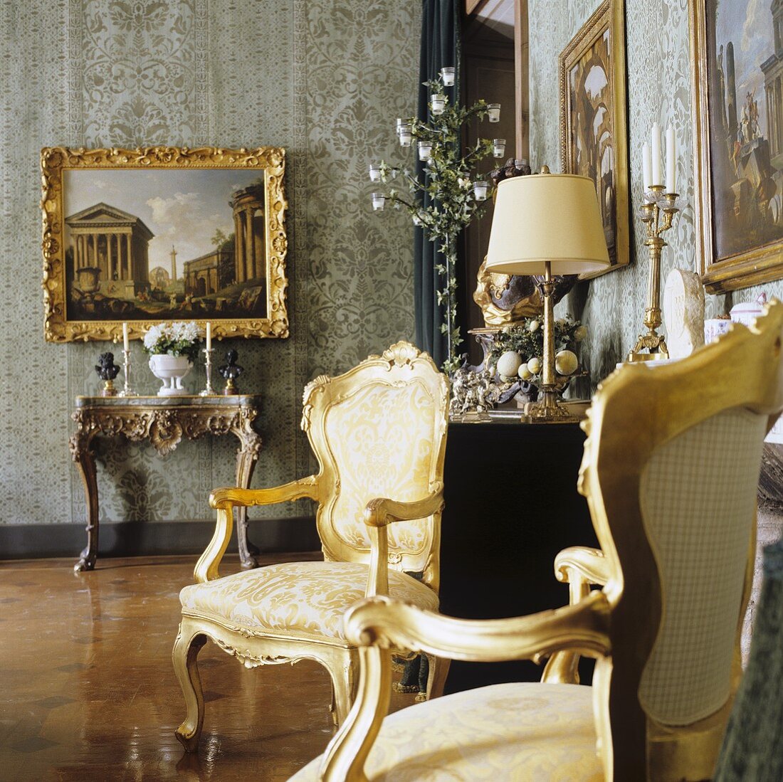Rococo chairs with gilded frames and a picture hanging above a wall table in a palazzo