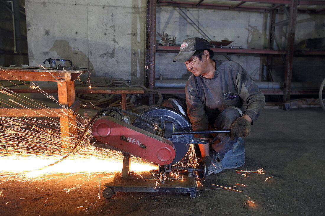 Fabrikarbeiter an einer Stahlschneidemaschine in einer Ziegelfabrik, Ulaanbaatar, Mongolei