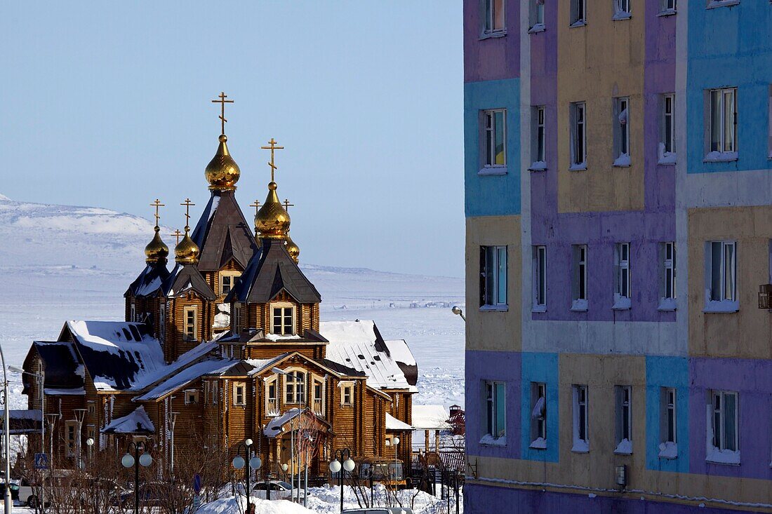 Orthodoxe Kathedrale der Heiligen Dreifaltigkeit neben farbigem Apartmenthaus, Anadyr, Tschukotka (Autonomer Kreis der Tschuktschen), Sibirien, Russland