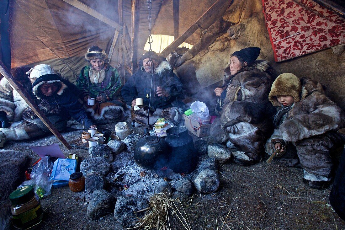 Annuitant nomad family around the fire in the Tschottagin, the awning of the Yaranga, Chukotka Autonomous Okrug, Siberia, Russia