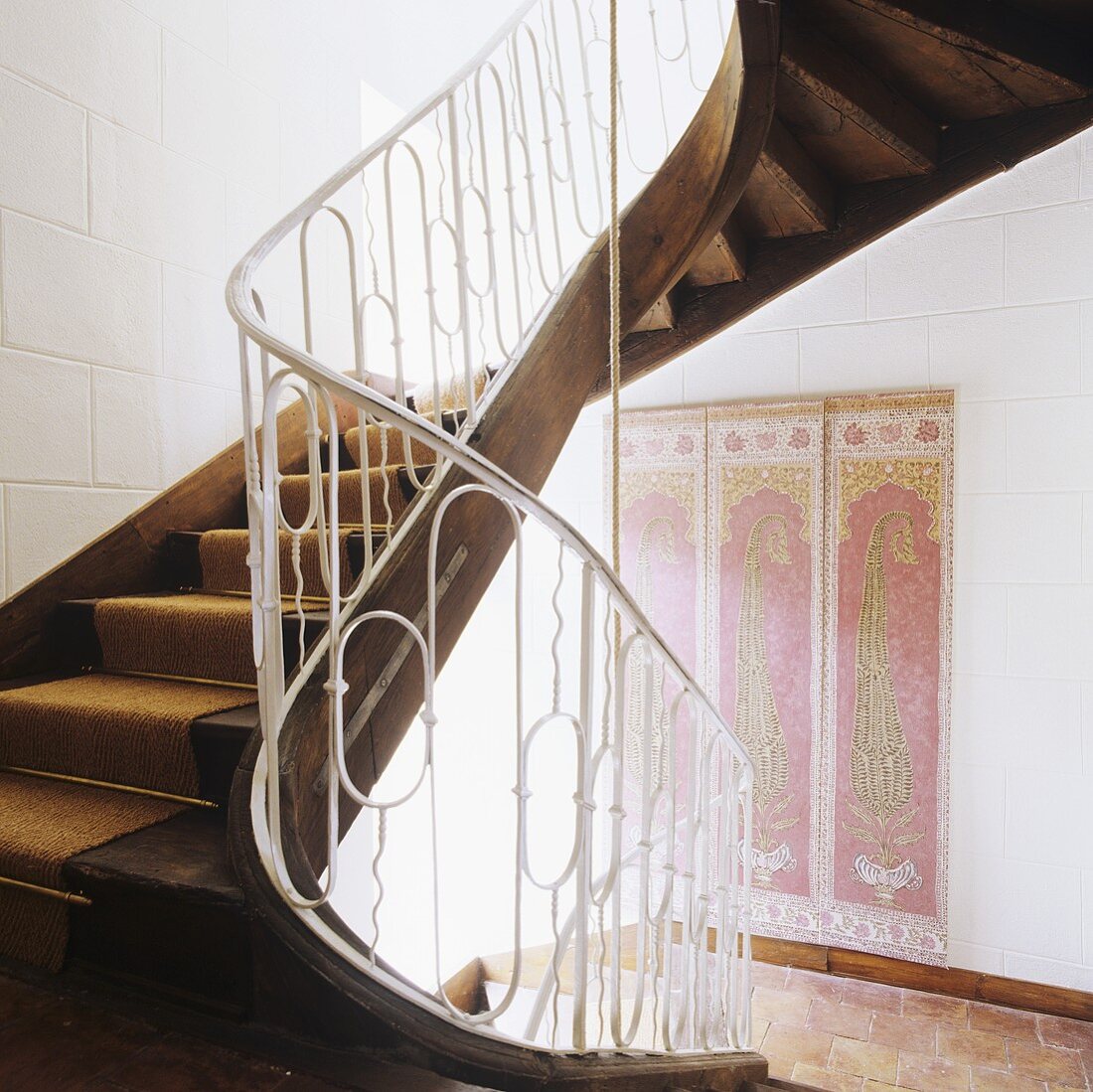 A curved wooden stairway with a white metal banister