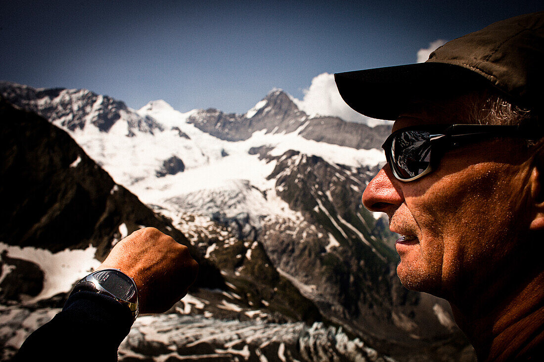 Hiker having a look at a watch, on the way to Schreckhorn hut, Lower Grindelwald glacier, Eiger and Moench in the background, Bernese Oberland, Switzerland