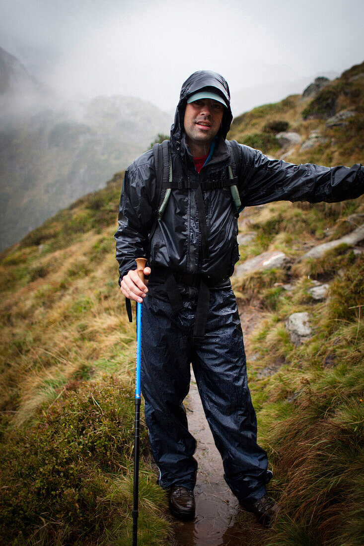Mann im Regen auf einem Bergpfad, Abstieg von der Bremer Hütte (2413 m), Hinteres Gschnitztal, Stubaier Alpen, Tirol, Österreich