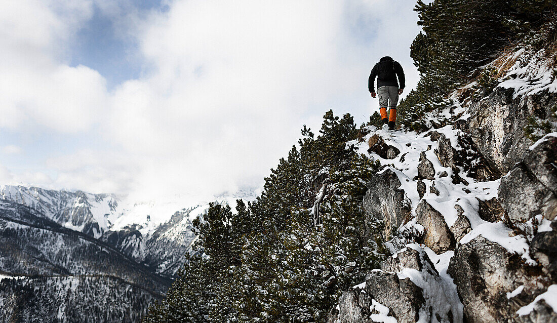 Hiker climbing over snow-covered rocks, ascend to Unnutz Mountain (2078 m), Rofan Mountains, Tyrol, Austria