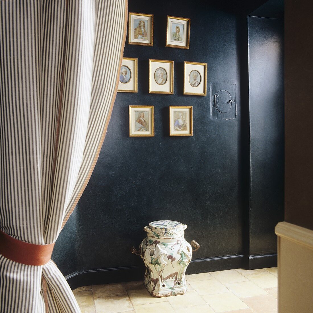 A view of a black wall hung with pictures in gold frames