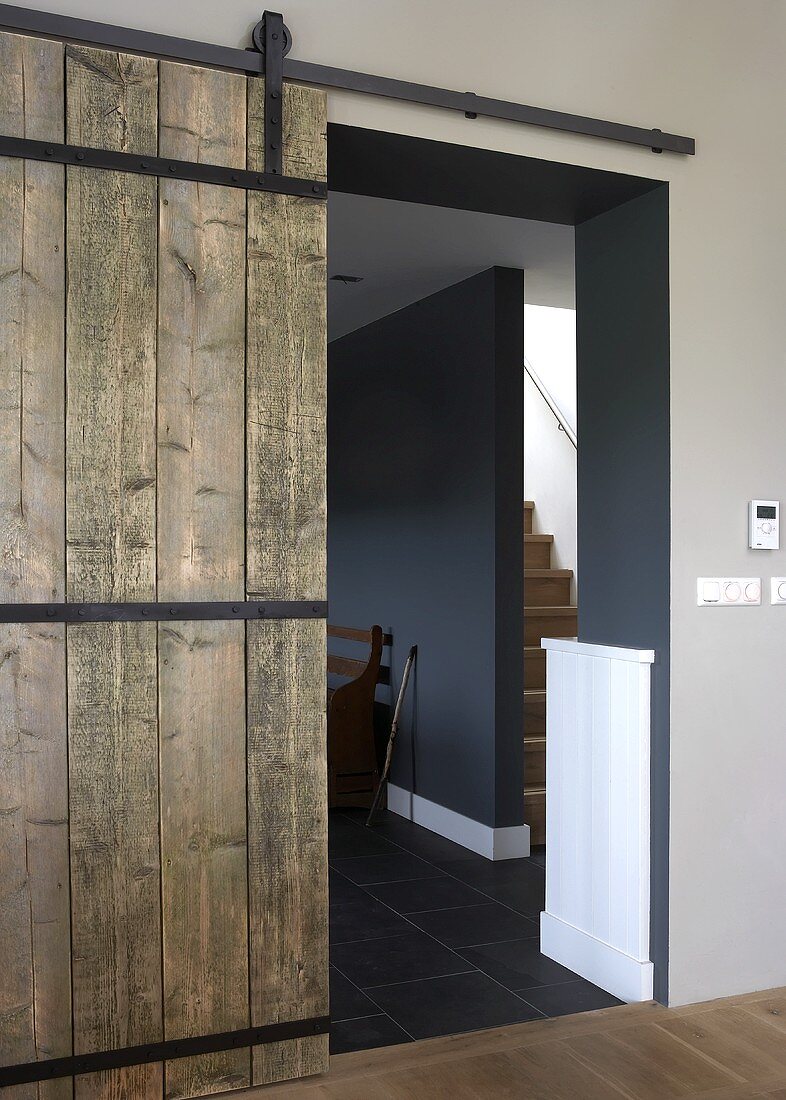 A rustic wooden sliding door from a hallway into a designer apartment