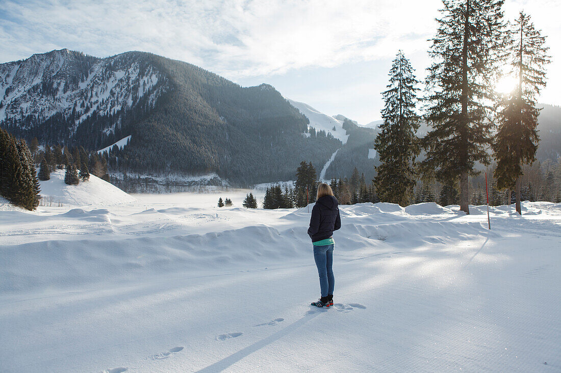 Junge Frau steht im Schnee, Spitzingsee, Oberbayern, Bayern, Deutschland