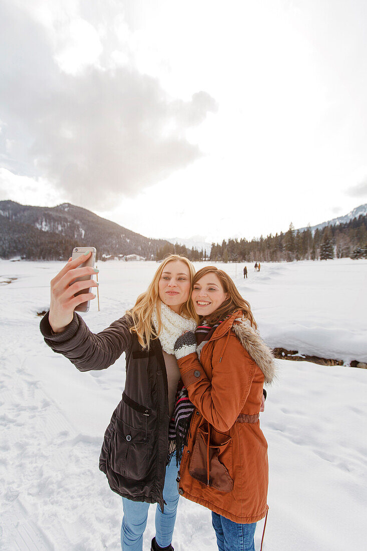 Two young women taking a selfie picture, Spitzingsee, Upper Bavaria, Germany