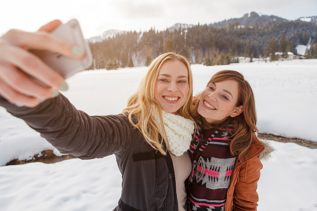 Two young women taking a selfie picture, Spitzingsee, Upper Bavaria, Germany