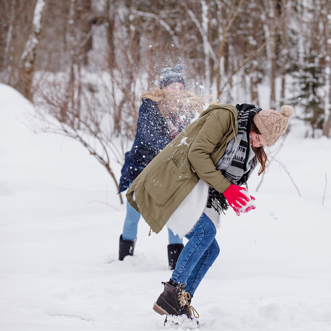 Two young women enjoying snowball fight, Spitzingsee, Upper Bavaria, Germany