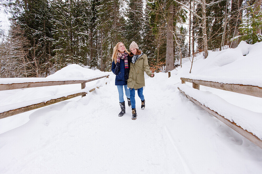 Zwei junge Frauen spazieren im Schnee, Spitzingsee, Oberbayern, Bayern, Deutschland