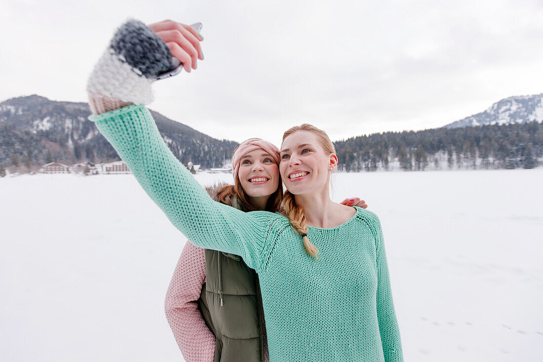 Two young women photographing themselves, Spitzingsee, Upper Bavaria, Germany