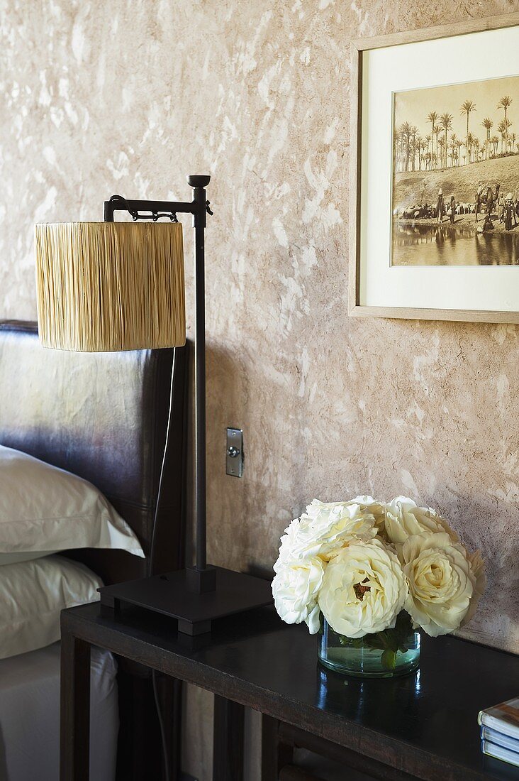 A table lamp and a vase of flowers on a dark wooden shelf