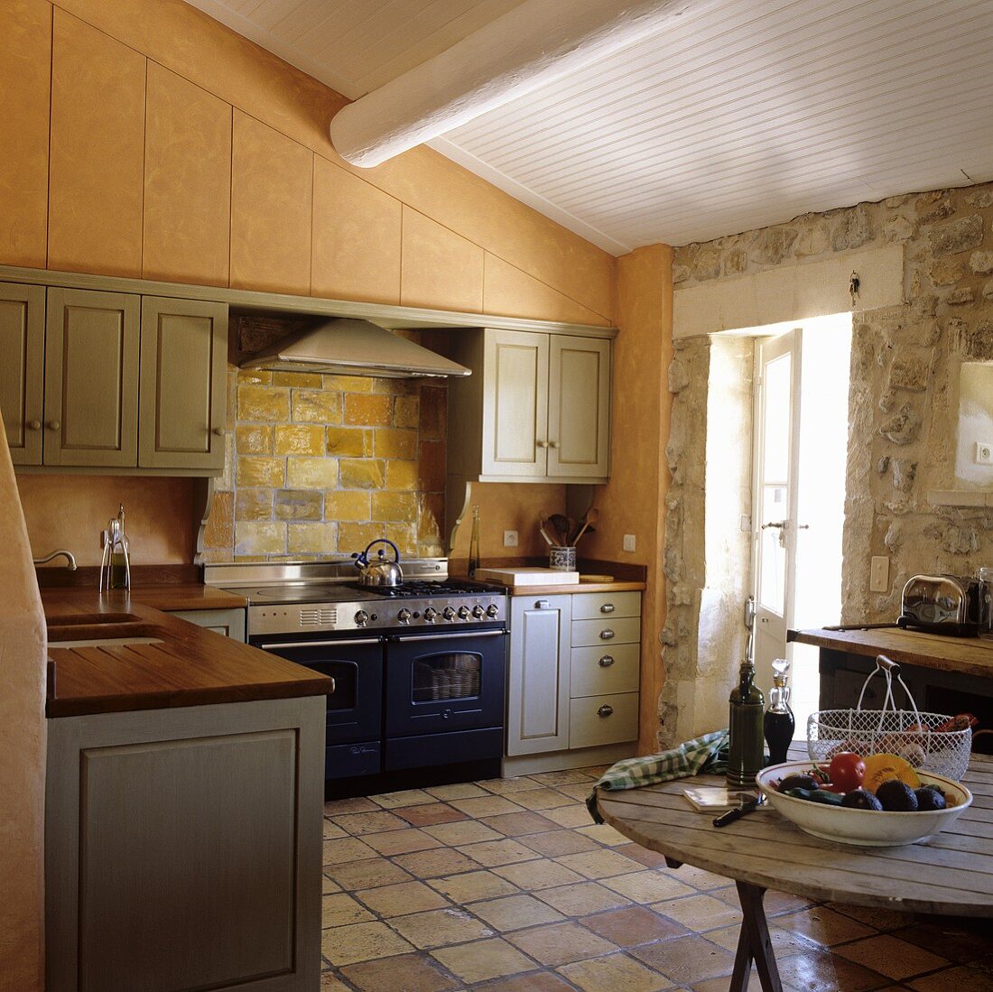 A kitchen in a country house with a natural stone wall