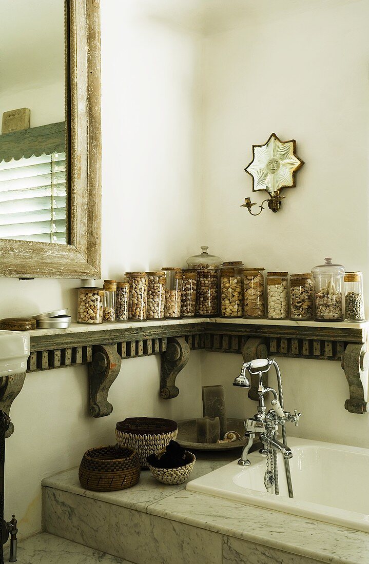 A corner of a bathroom with storage jars on a carved wooden shelf