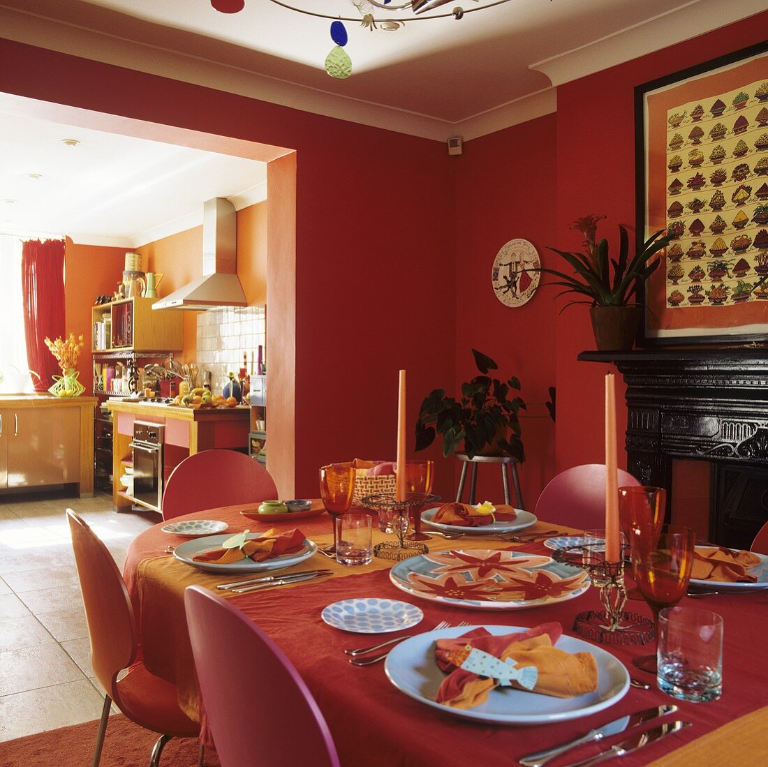 A brick red dining room with a laid table and view through a doorway into a kitchen