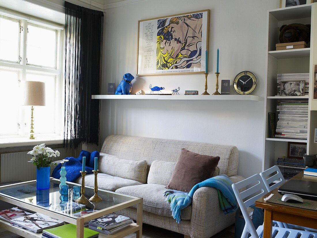 Bright gray sofa with white wall shelf and coffee table next to a window