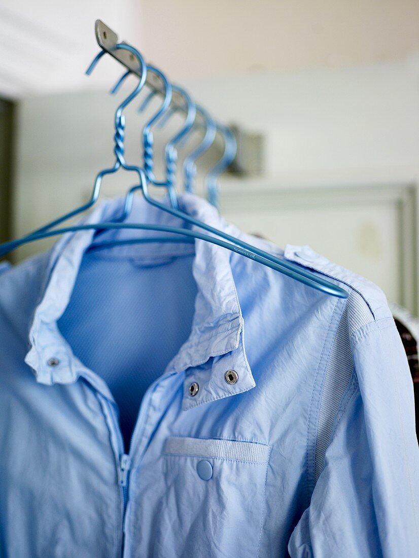 Coat hangers with a bright blue wind breaker hanging on a rack