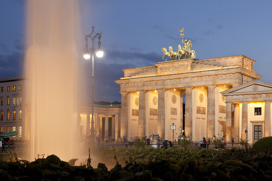 the illuminated Brandenburg Gate and fountain on Pariser Platz in Berlin, Germany, Europe.