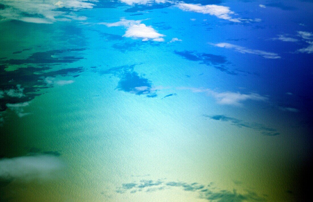aerial view of calm blue sea ocean texture surface with clouds, shadows and islands
