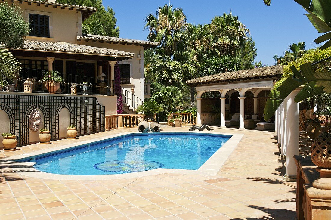 Swimming pool surrounded by large patio with summer house