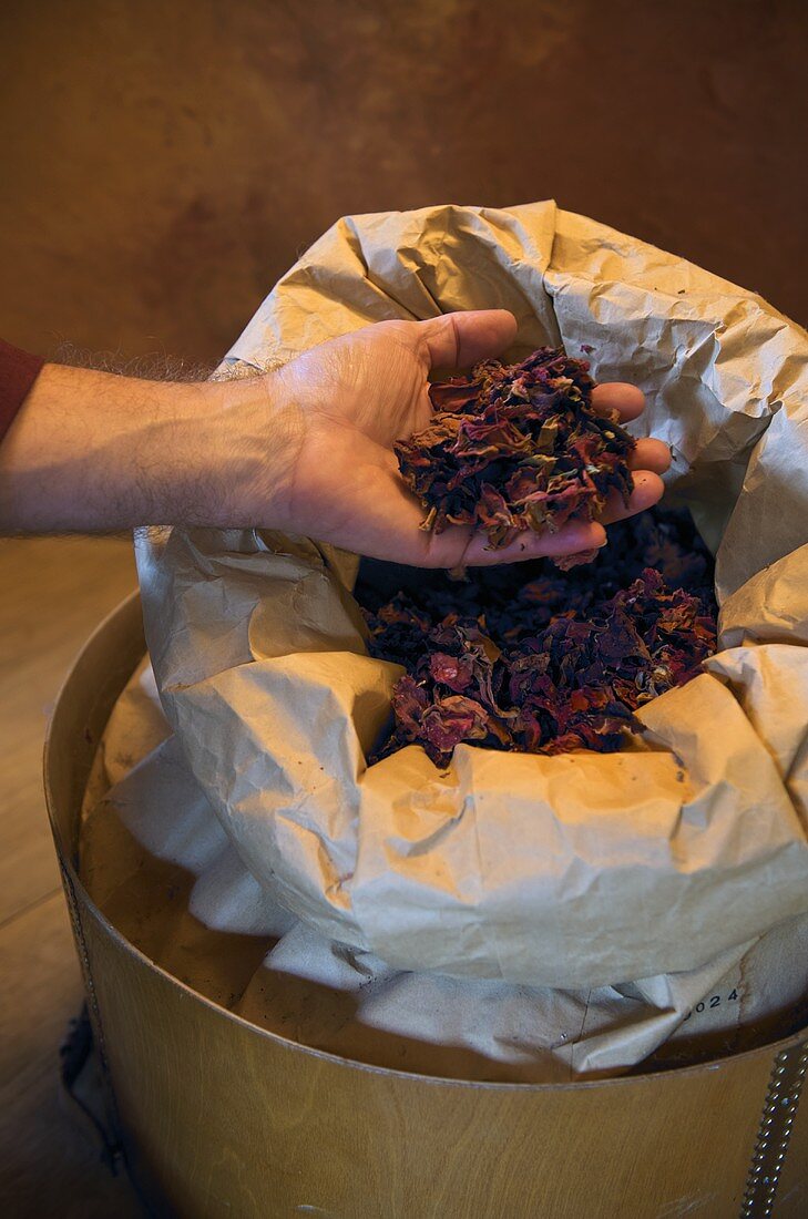 Hand holding dried petals from an open paper bag