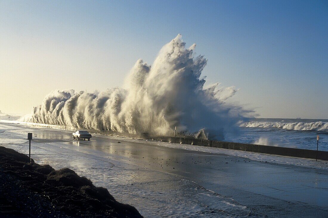 Storm surge wave crashs into Highway One at Solimar Beach, California with a car driving