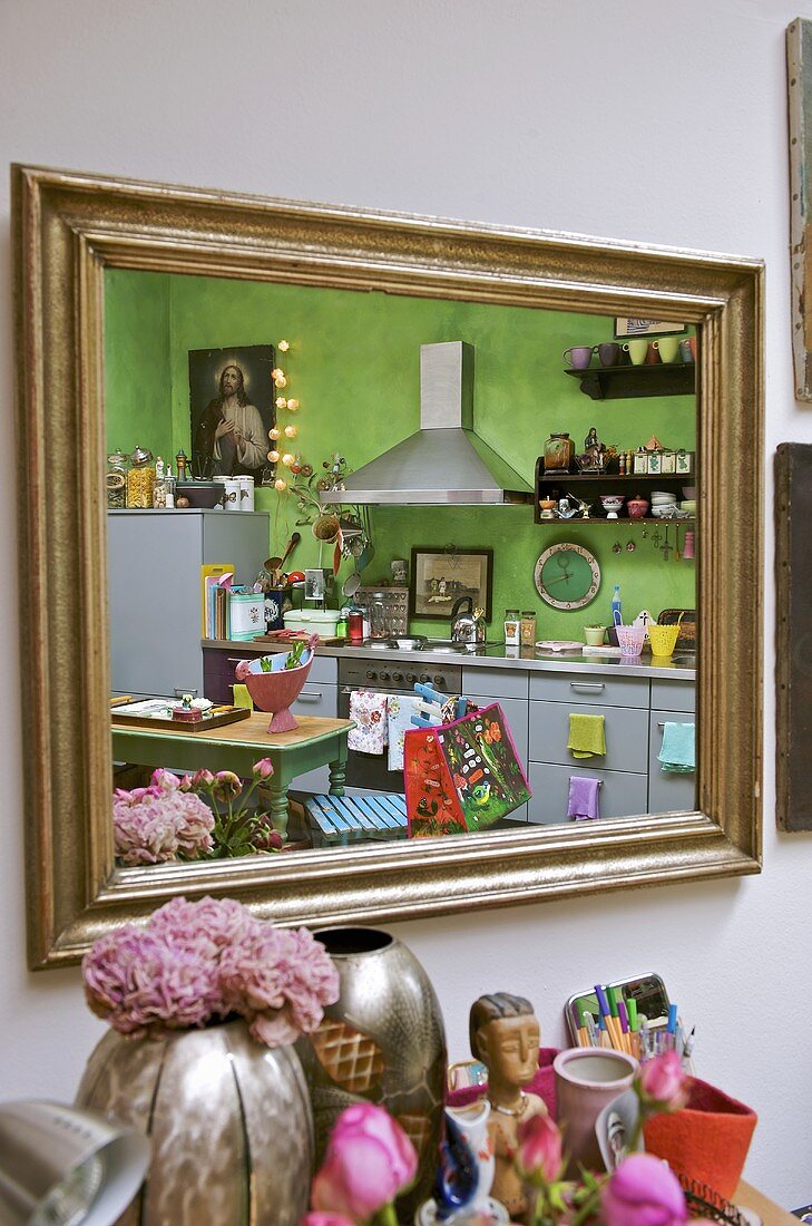 Moderne Küche mit Stilmixmöbeln und grüner Wand reflektiert im Spiegel