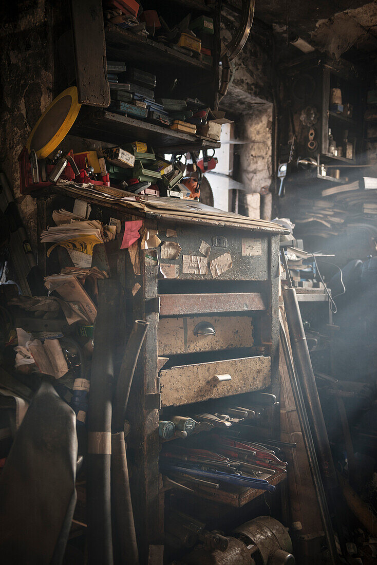 warmes Streiflicht fällt durch Fenster in chaotische Werkstatt eines Hammerschmieds, Vellberg, Landkreis Schwäbisch Hall, Baden-Württemberg, Deutschland