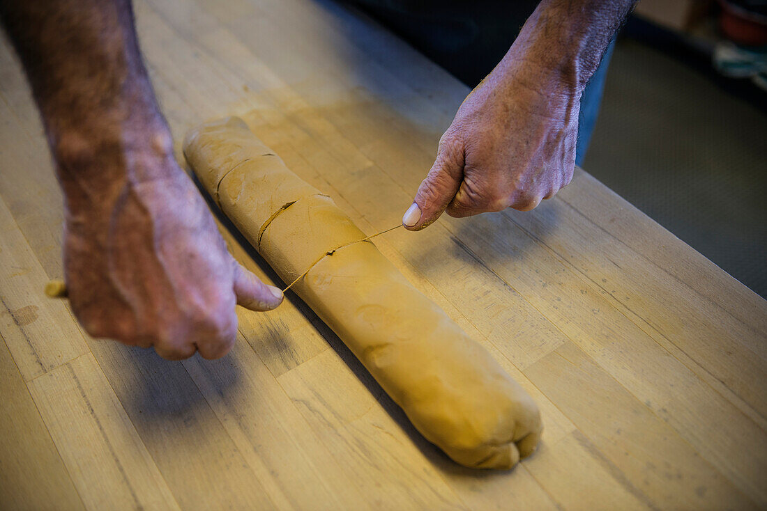 Clay being cut into pieces in the pottery, Vellberg, Schwaebisch Hall, Baden-Wuerttemberg, Germany