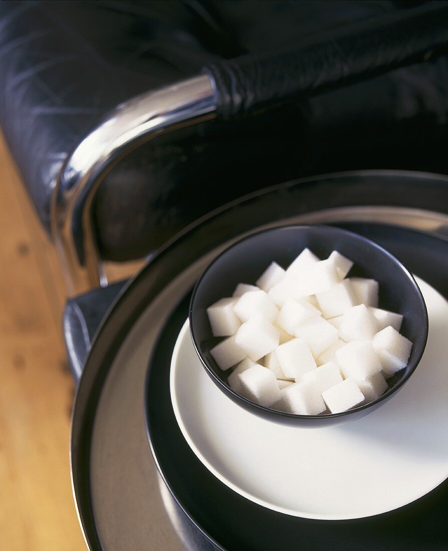 Sugar cubes in a black bowl on a white plate