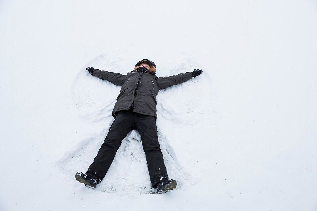 Frau macht einen Schneeengel in einer verschneiten Winterlandschaft im Kellerwald bei Dülfershof, Löhlbach, nahe Bad Wildungen, Nordhessen, Hessen, Deutschland, Europa
