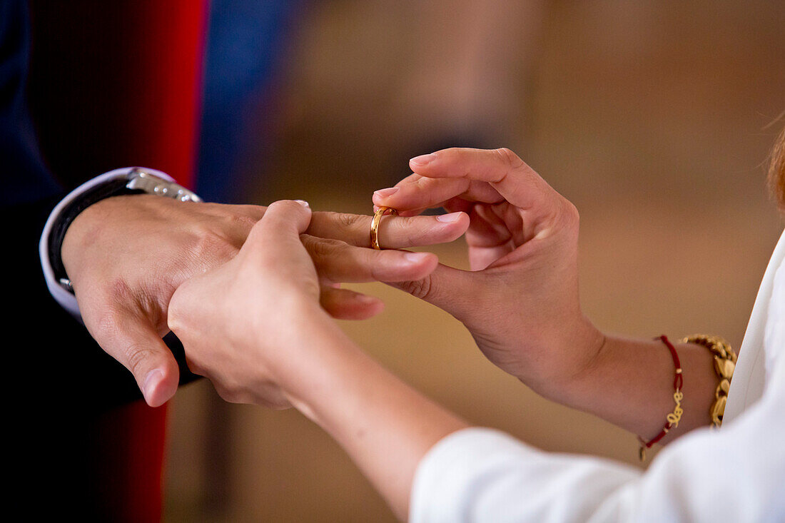 Close-up of bride's hands as she places the wedding ring onto the ring finger of groom's hand during marriage ceremony, Bad Wildungen, Hesse, Germany, Europe