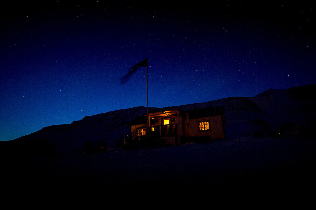 Beleuchtete Schutzhütte in der Nacht auf Spitzbergen, Svalbard, Norwegen