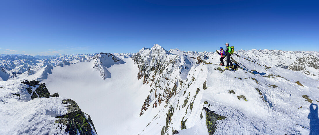 Panorama with man and woman back-country skiing looking towards Stubai Alps with Agglspitze, Feuersteine and Wilder Freiger, Schneespitze, valley of Pflersch, Stubai Alps, South Tyrol, Italy