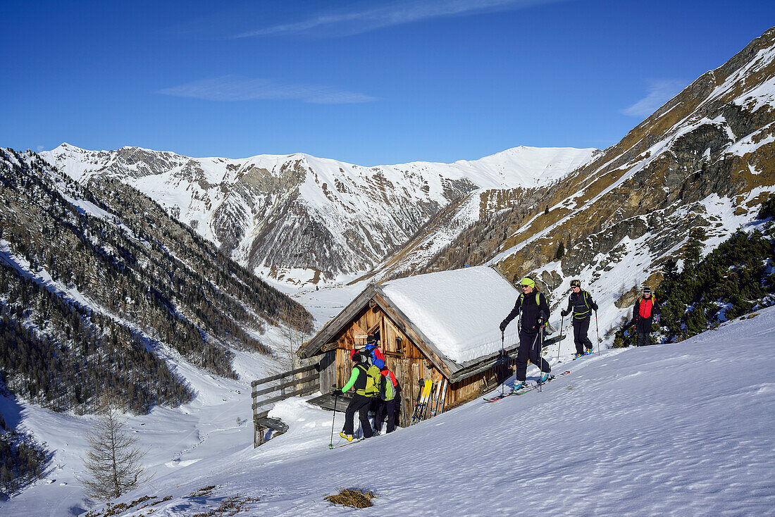Several persons back-country skiing standing in front of alpine hut, Frauenwand, valley of Schmirn, Zillertal Alps, Tyrol, Austria