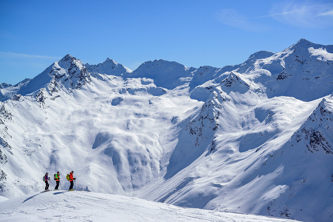 Drei Personen auf Skitour blicken auf Stubaier Alpen, Schneespitze, Pflerschtal, Stubaier Alpen, Südtirol, Italien