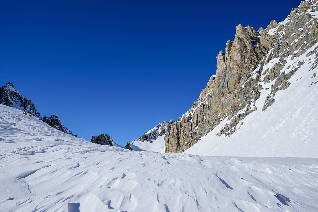 Snow erosion in front of rock wall of Monte Sautron, Valle Maira, Cottian Alps, Piedmont, Italy