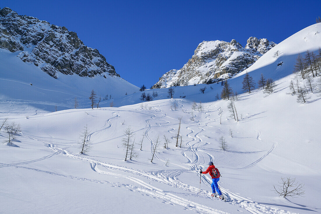 Frau auf Skitour steigt zum Passo Croce auf, im Hintergrund Rocca Peroni, Passo Croce, Valle Maira, Cottische Alpen, Piemont, Italien