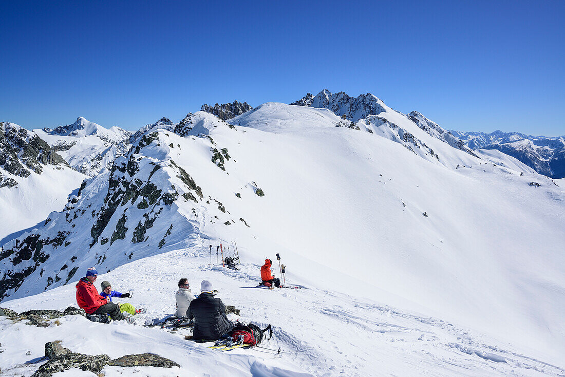 Mehrere Personen auf Skitour machen im Passo Croce Pause, Passo Croce, Valle Maira, Cottische Alpen, Piemont, Italien