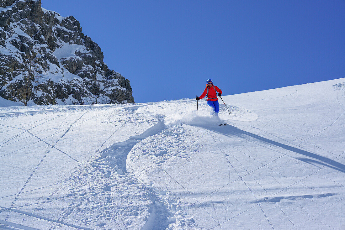 Frau auf Skitour fährt durch Pulverschnee vom Passo Croce ab, Passo Croce, Valle Maira, Cottische Alpen, Piemont, Italien
