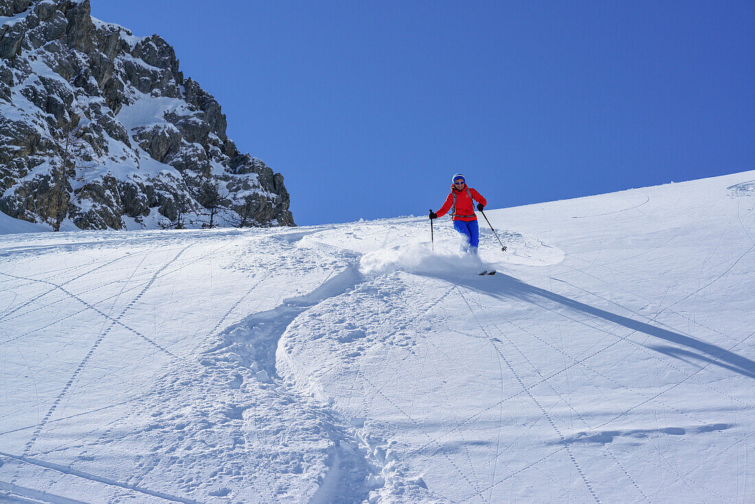 Woman back-country skiing downhill through powder snow from Passo Croce, Passo Croce, Valle Maira, Cottian Alps, Piedmont, Italy