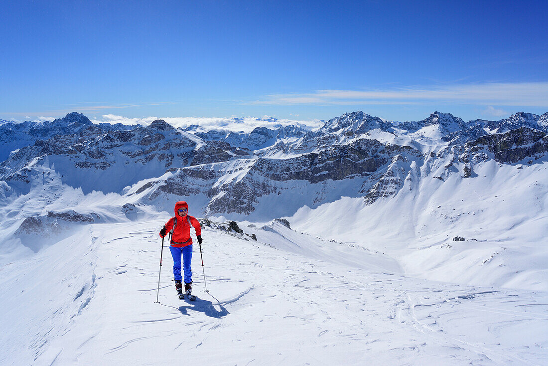 Woman back-country skiing ascending towards Monte Faraut, in background Tete de Moise, Monte Cervet, Monte Sautron and Rocca Blancia, Monte Faraut, Valle Varaita, Cottian Alps, Piedmont, Italy