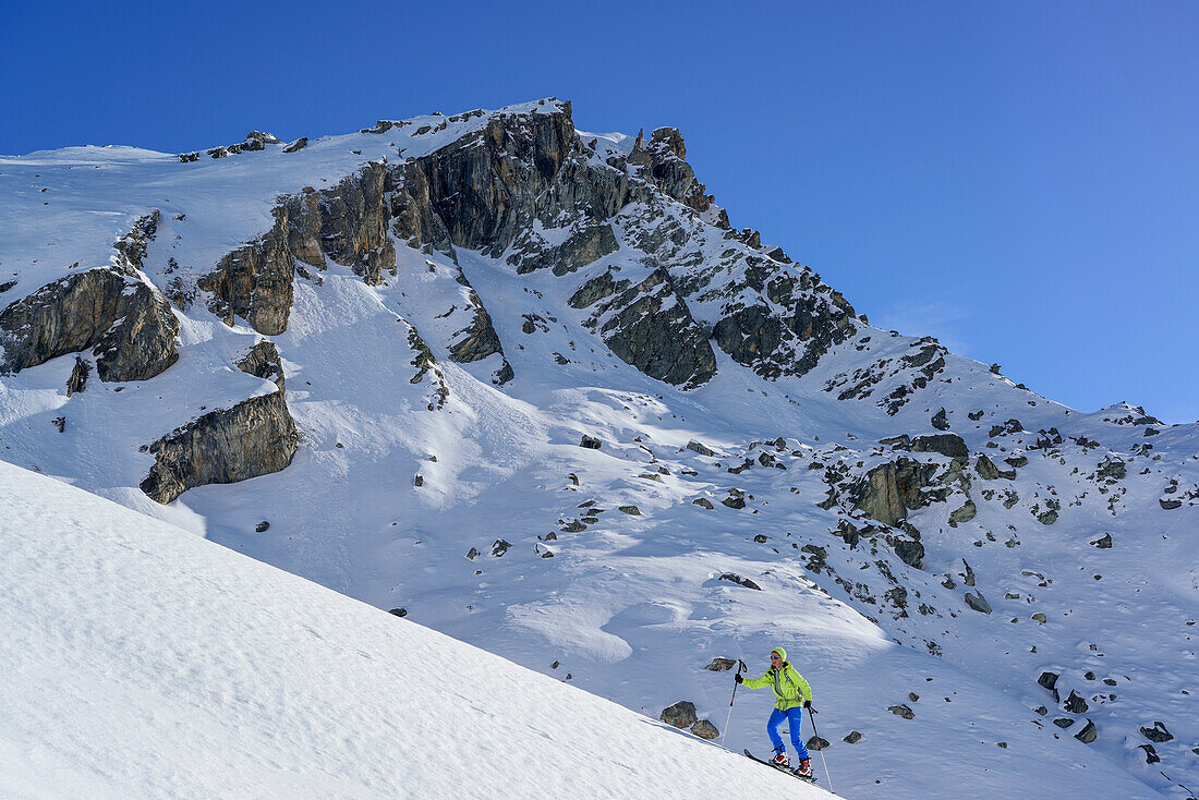 Woman back-country skiing ascending towards Monte Salza, Monte Salza, Valle Varaita, Cottian Alps, Piedmont, Italy