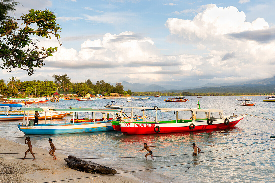 Children playing in the water, boats at beach, Gili Air, Lombok, Indonesia